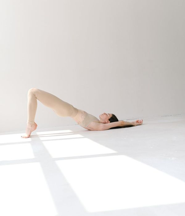 Woman in a calm yoga pose in a studio with golden light.